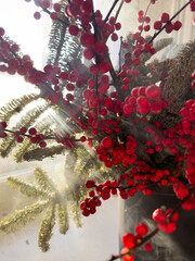 a bouquet of branches with red berries and fir branches in smoke in sunny weather, the rays of the sun through the branches