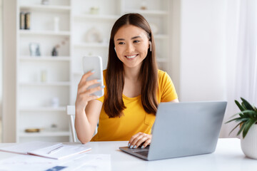 Woman taking selfie with smartphone and laptop