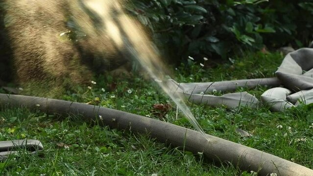 Damaged water hose leaking and spraying in slow motion