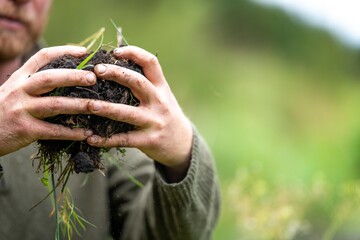 agricultural farmer Holding soil in a hand, feeling compost in a field in Tasmania Australia. soil...