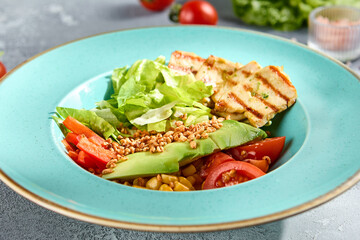 Grilled chicken fillet and avocado salad bowl with fresh veggies on a sun-kissed tabletop