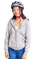 Young beautiful chinese girl wearing bike helmet looking positive and happy standing and smiling with a confident smile showing teeth