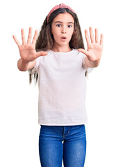 Cute hispanic child girl wearing casual white tshirt doing stop gesture with hands palms, angry and frustration expression