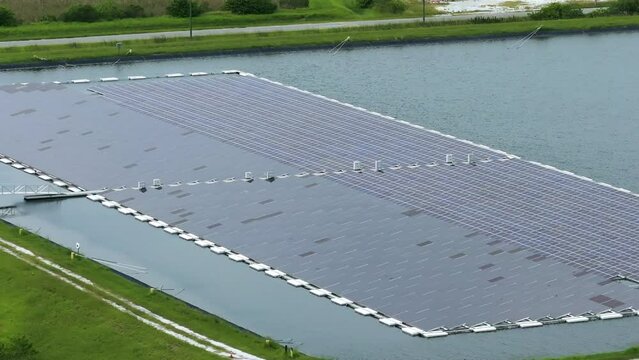 Industrial pond with floating photovoltaic solar panels for producing clean electrical energy. Concept of renewable electricity on water surface with no air pollution
