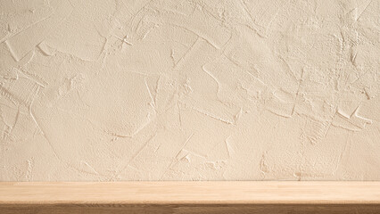 A close-up view showcasing the texture of a beige wall above a smooth wooden shelf, reflecting a...
