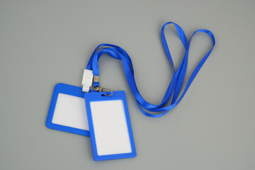 Two blue badges with strings on grey background	