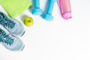 Sneakers, dumbbells, green apple and bottle of water isolated on white background.