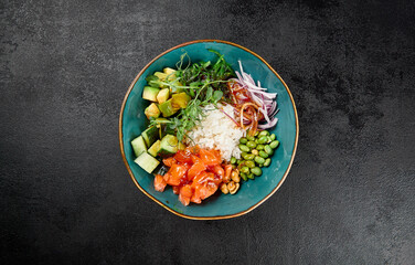 Poke bowl with salmon and vegetables on black concrete background. Ahi poke with salmon, rice,...