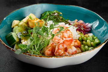 Poke bowl with shrimps and vegetables on black concrete background. Ahi poke with shrimp, rice,...