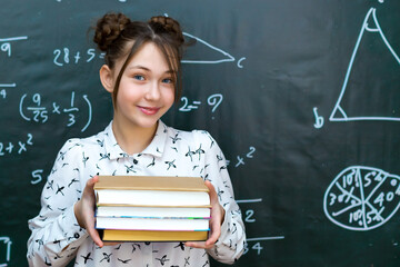 Girl schoolgirl with four books in her hands, concept of school life preparing exams.