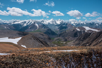 Dramatic ascetic aerial view above precipice edge on high stony snowy pass to alpine valley and...