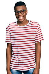 Young african american man wearing casual t shirt and glasses with a happy and cool smile on face....