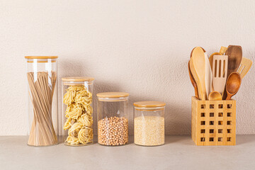 A set of glass jars with a bamboo lid for storing bulk food stand in a row next to a stand with...