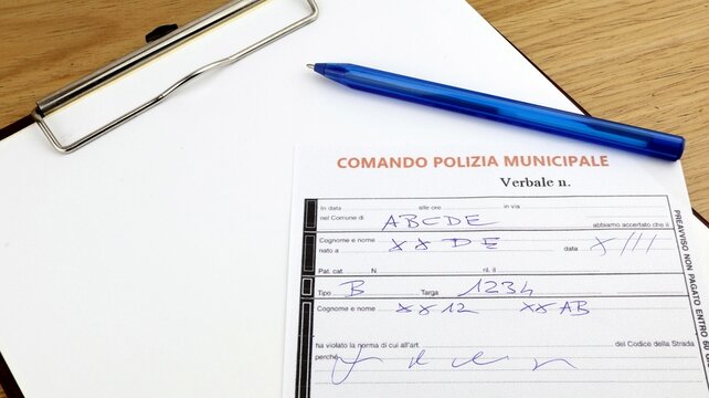 Verbal fine for traffic infringement "Italian Municipal Police" sheet on the desk.