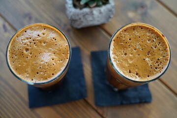 Top view of two glasses of iced cold frappes on a wooden table