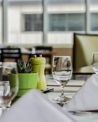 Shallow focus of cactus plant, wine glass, salt and pepper mill, on a table with blur background