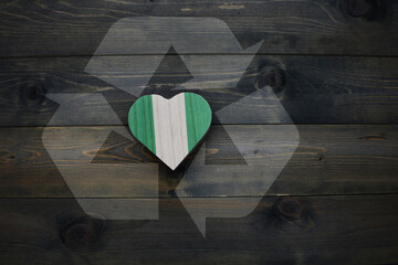 wooden heart with national flag of nigeria near reduce, reuse and recycle sing on the wooden...