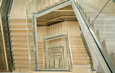 High angle shot of a spiral staircase with wooden stairs and glass railings