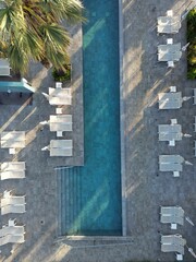 Vertical top view of a long swimming pool and beach chairs in a luxurious resort