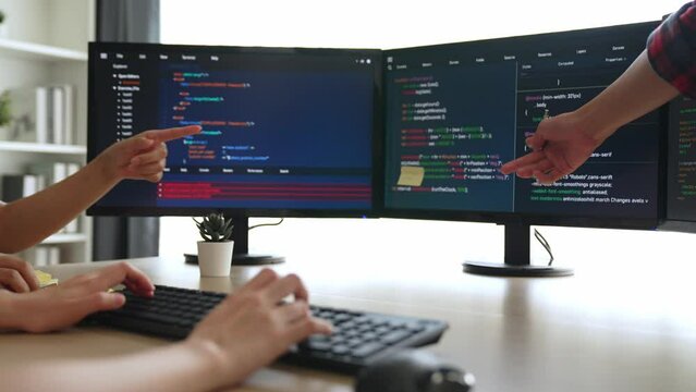 Slow motion back end software developer engineer for computer programming working together on debugging writing computing code, solving complex algorithms display on monitor in office. Burgeoning