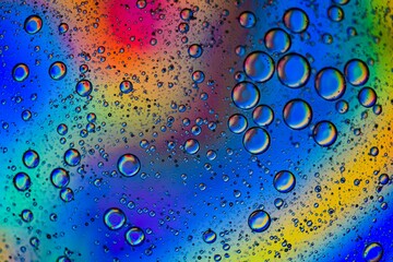 Close-up shot of oil drops in colorful water surface