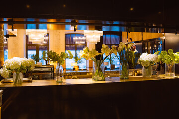 Beautiful flowers displayed in vases adorn the counter of a restaurant, adding a touch of elegance...