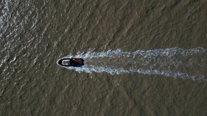 Aerial drone view of a boat speeding on a dirty water