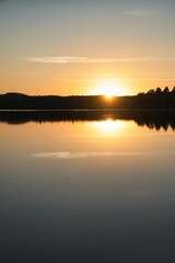 Obraz premium Vertical shot of a beautiful bright sunrise over the lake shore