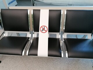 Row of waiting hall chairs with a restriction sign for keeping social distancing