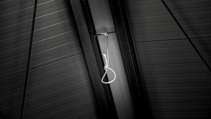 Low-angle shot of a rope tied round from the ceiling in black and white. - obrazy, fototapety, plakaty