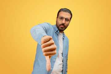 Man giving thumbs down on yellow backdrop