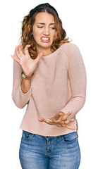 Beautiful young caucasian woman wearing casual sweater disgusted expression, displeased and fearful...