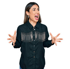 Young hispanic woman wearing casual clothes crazy and mad shouting and yelling with aggressive...