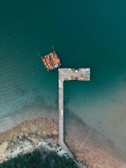 Vertical shot of a pier and shore with layered color sea