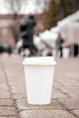Eco paper coffee cup on the asphalt with empty copyspace, vertical