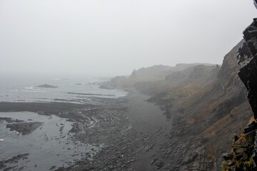Landscape of hills canyon coast by the sea with misty cloudy sky on the horizon