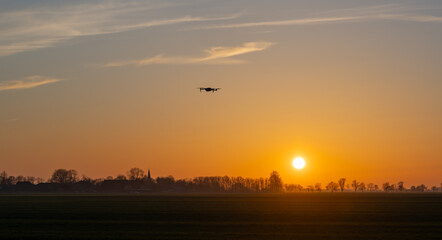 Drohne fliegt einem intensiven Sonnenuntergang durch Sahara Staub entgegen - obrazy, fototapety, plakaty