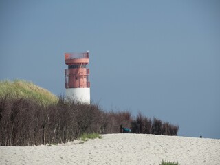 Lighthouse on a sandy beach with green grass in Helgoland, Germany.