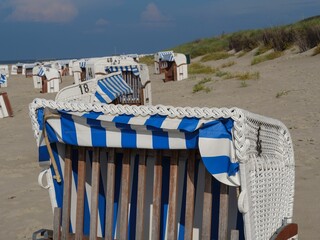 Numbered beach chairs on the sand under blue sky in Spiekeroog town, Germany