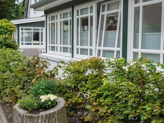 Cozy little house on Spiekeroog, Germany with bright green trees outside it on a sunny day