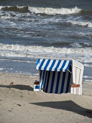 Vertical image of a sandy beach with a chair in front of the North Sea in Wangerooge, Germany