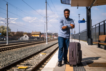 Fototapeta na wymiar Happy man with suitcase standing on railway station. 