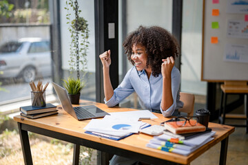 Happy african american woman celebrating victory while receiving good news on her labtop, excited...
