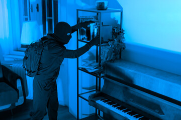 Thief searching through shelving unit next to piano