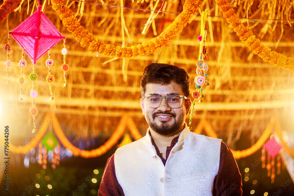 Wall mural Indian man in traditional wear or kurta pyjama cloths. Male fashion model in sherwani, posing / standing against wedding mandap background