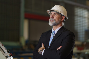 A man in a suit and a hard hat stands in front of a building
