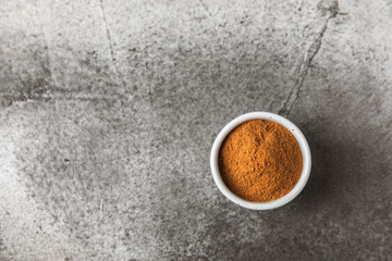 Cinnamon powder in a bowl on a textured wooden background. Spicy spice for baking, desserts and drinks. Fragrant ground cinnamon. Cinnamon stick. Place for text. Copy space.