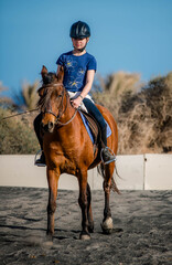 Beautiful young girl riding her horse in the desert and dunes of Fuerteventura