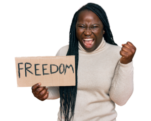 Young black woman with braids holding freedom banner screaming proud, celebrating victory and success very excited with raised arms
