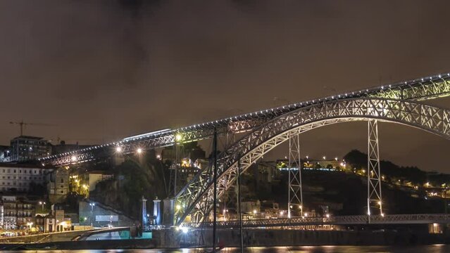 Porto, Portugal old town skyline on the Douro River at night with rabelo boats with illuminated Luis I Bridge timelapse hyperlapse. City lights reflected in water